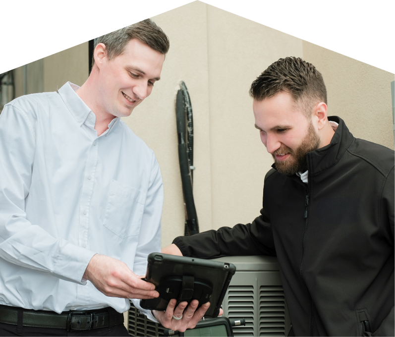 A Mersey technician in a white shirt shows service details on a tablet to a smiling client in a black jacket, standing beside an AC unit outside a beige building. A Mersey technician in a white shirt shows service details on a tablet to a smiling client in a black jacket, standing beside an AC unit outside a beige building.