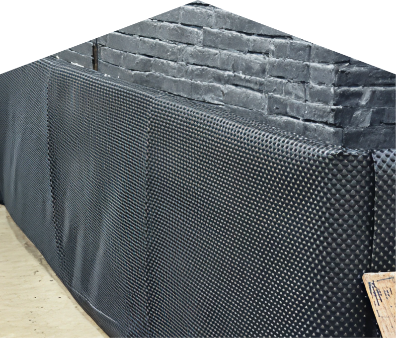 Exterior basement waterproofing completed by Mersey, showing a sealed foundation wall with dimpled waterproof membrane partially installed on a brick surface, preventing moisture infiltration. Exterior basement waterproofing completed by Mersey, showing a sealed foundation wall with dimpled waterproof membrane partially installed on a brick surface, preventing moisture infiltration.