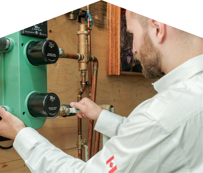Mersey HVAC specialist performing boiler installation, securing a valve on a new hydronic heating system with copper piping and a green circulation pump mounted on a wooden wall. Mersey HVAC specialist performing boiler installation, securing a valve on a new hydronic heating system with copper piping and a green circulation pump mounted on a wooden wall.