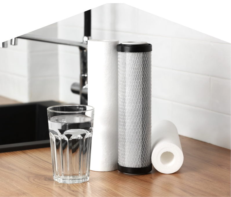 Set of Mersey water filtration cartridges placed beside a clear glass of water on a kitchen countertop, with a sink and modern faucet in the background. Set of Mersey water filtration cartridges placed beside a clear glass of water on a kitchen countertop, with a sink and modern faucet in the background.