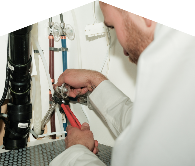 Mersey plumbing expert tightening connections under a sink during a faucet installation, surrounded by hot and cold water supply lines and PVC drainage. Mersey plumbing expert tightening connections under a sink during a faucet installation, surrounded by hot and cold water supply lines and PVC drainage.