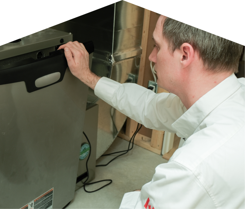 Mersey HVAC professional installing a new furnace unit, aligning the front panel with surrounding ductwork and wiring in a residential utility space. Mersey HVAC professional installing a new furnace unit, aligning the front panel with surrounding ductwork and wiring in a residential utility space.
