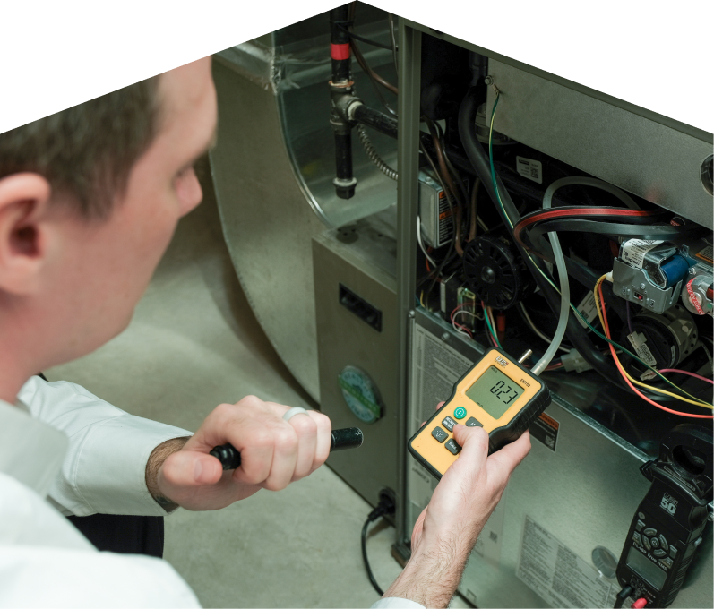 Mersey HVAC specialist performing furnace repair on a heating system, using a digital manometer to check pressure. Mersey HVAC specialist performing furnace repair on a heating sy