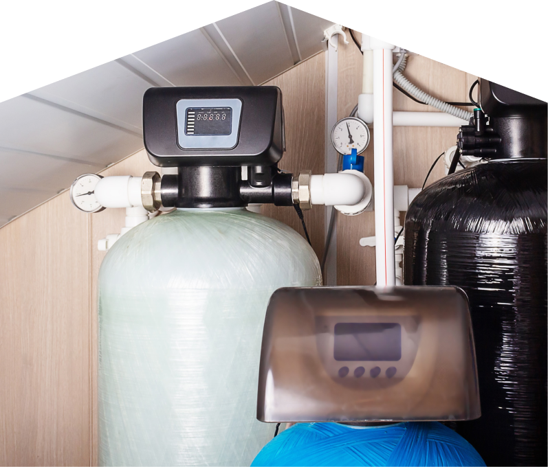 Mersey home water filtration system featuring resin tanks, digital control heads, pressure gauges, and connected piping in a utility room. Mersey home water filtration system featuring resin tanks, digital control heads, pressure gauges, and connected piping in a utility room.