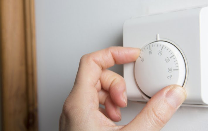 hand adjusting a thermostat