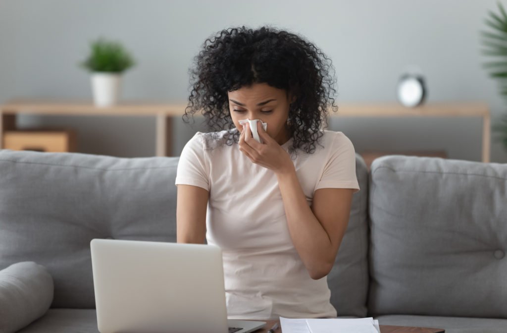 Woman blowing her nose because her ducts need to be cleaned.